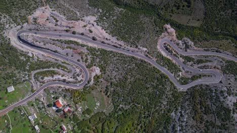 Winding-mountainside-road-on-the-rocky-side-of-the-alpine-mountains-near-a-tourist-village-in-Albania