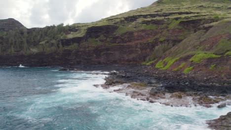 Cinematic-footage-of-azure,-blue,-green,-turquoise-waves-crashing-on-scenic-black-volcanic-sea-cliffs-and-sharp-rocks