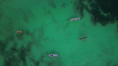 Small-boats-anchored-in-shallow-waters-at-Uroa-beach-Zanzibar-Island,-Tanzania-Africa,-Aerial-top-view-rotating-shot