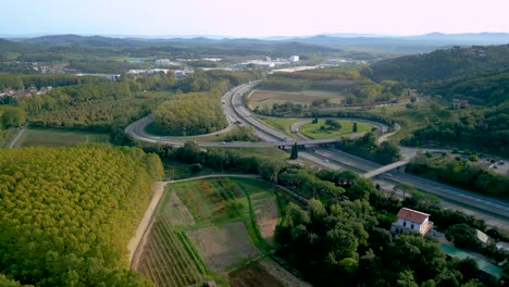Aerial-image-of-the-motorway-road-C32-Barcelona-France,-flowing-traffic-of-cars-lush-green-vegetation