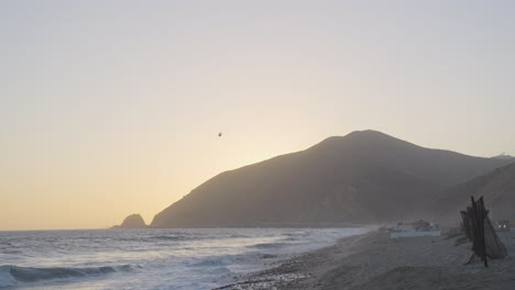 Distance-tracking-shot-of-helicopter-flying-over-Mondo's-Beach-located-in-southern-California-during-the-golden-hour