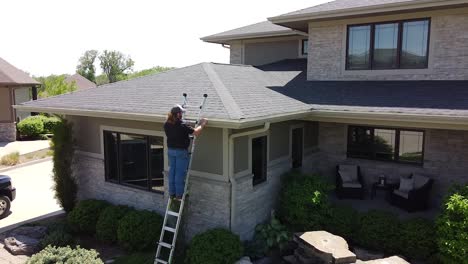 Drone-shot-of-a-Gutter-inspection-from-a-ladder-by-a-handy-man-carpenter