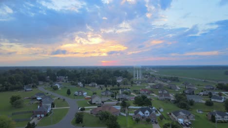 Drone-flying-towards-the-watertower-in-Clarksville-with-a-bus-on-the-road-revealing-a-beautiful-sunrise-with-clouds-in-the-sky