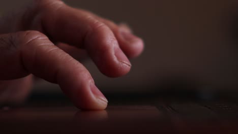 Close-up-of-man's-fingers-scrolling-and-tapping-the-track-pad-on-his-laptop-backlit-by-the-screen