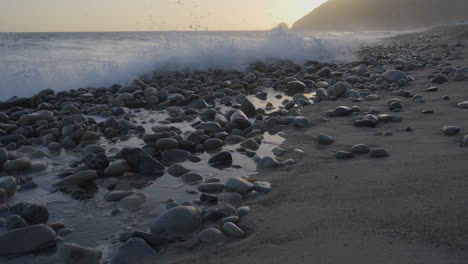 Panning-shot-of-waves-crashing-into-the-rocky-shores-of-Mondo"s-Beach-located-in-Southern-California-at-golden-hour