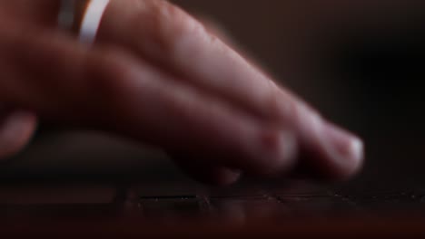 Close-up-side-view-of-man's-hands-typing-on-his-laptop-backlit-by-the-screen