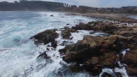 Rough-sea-waves-crashing-on-rocky-shore,-dramatic-FPV-aerial-view