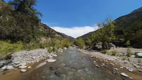 Flying-along-river-bed-in-rocky-Cajon-del-Maipo-canyon-in-Chile,-FPV-low-flying-shot