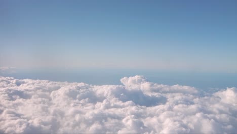 Motion-shot-from-the-window-of-an-airplane-with-fluffy-clouds-beneath