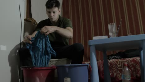 A-young-caucasian-man-washes-clothing-by-hand-indoors