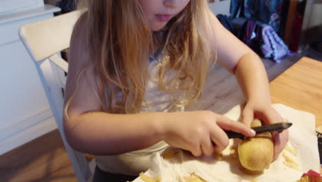 Ein-Mädchen-Am-Tisch-Mit-Rosa-Schlafbrille-Schält-Zum-Mittagessen-Kartoffeln