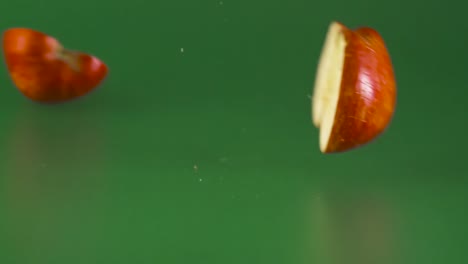 Roter-Apfel-Fällt-Und-Bricht-Auf-Grünem-Hintergrund-In-Zwei-Hälften