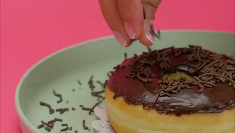 Chocolate-being-sprinkled-on-a-donut-by-a-women-chef