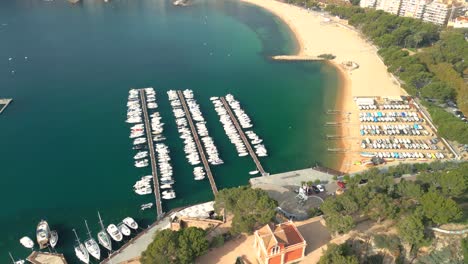 Aerial-image-of-Sant-Feliu-de-Guíxols-from-the-port-towards-the-main-beach-with-the-city-in-the-background