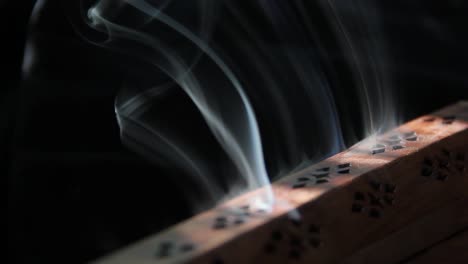 Incense-smoke-curls-out-of-a-wooden-incense-burner