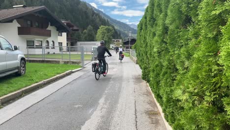 Ciclistas-En-Un-Carril-En-Tirol,-Austria-Mostrando-Una-Casa-De-Pueblo