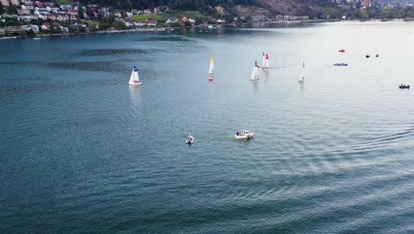 Aerial-drone-footage-following-a-motor-boat-approaching-sailboats-on-Lake-Biel-and-showing-off-the-blue-waters-and-gorgeous-scenery