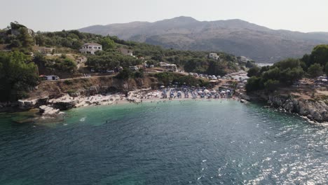 Aerial-View-Of-Busy-Kassiopi-Beach-In-Corfu-On-Sunny-Day