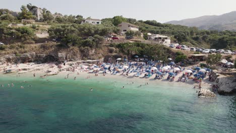 Aerial-View-Of-Busy-Kassiopi-Beach-In-Corfu-On-Sunny-Day