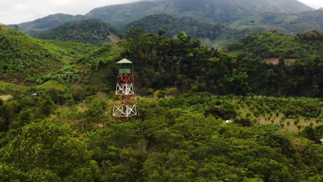 Aerial-zoom,-fire-lookout-tower-in-the-middle-of-lush-green-tropical-forest