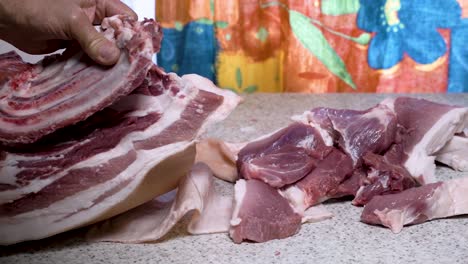 Pork-splitting-process,-separating-ribs-from-the-loin-on-kitchen-table,-medium-shot