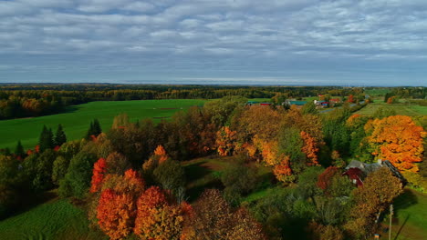 Fall-season-countryside-landscape,-Lakefront-house-surrounded-by-Vibrant-color-trees,-Aerial-backward