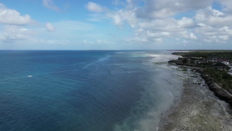Kusini-beach-shore-with-a-resort-near-the-rock-wall-in-East-Zanzibar-Island-Tanzania-Africa,-Aerial-rising-reveal-shot