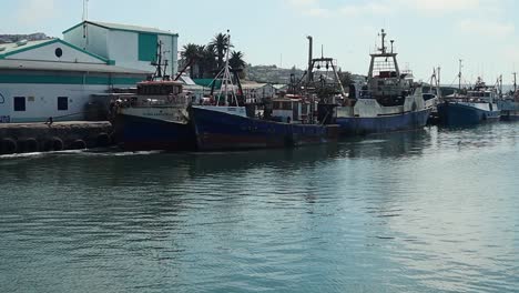 Pan-shot-of-fishing-boats-docked-in-calm-harbour