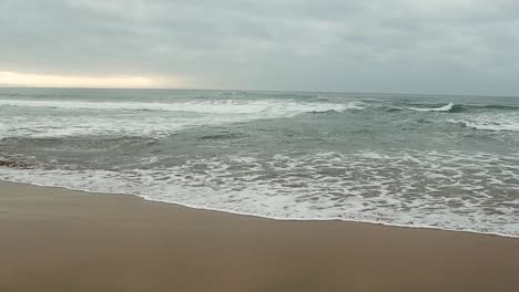 Kleine-Wellen,-Die-An-Die-Sandige-Küste-Brechen