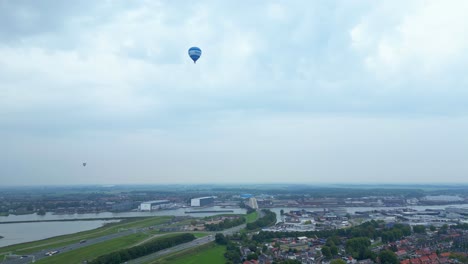 Blue-Hot-Air-Balloon-Flying-Across-Hendrik-ido-Ambacht-Town-Under-Clouds