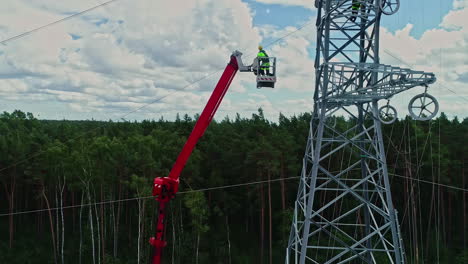 Electrician-On-An-Elevated-Working-Platform-Next-To-Transmission-Tower-During-Daytime