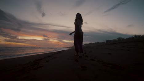 Following-A-Woman-Walking-Alone-On-Sandy-Shore-During-Sunset