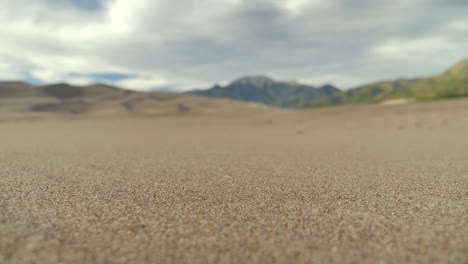 Cinematic-Push-In-Close-Up-of-Sandy-Desert-with-Pull-Focus-Revealing-the-Background-Mountain-Range
