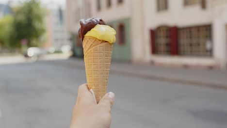Holding-Gelato-Ice-cream-against-city-views-in-background,-handheld