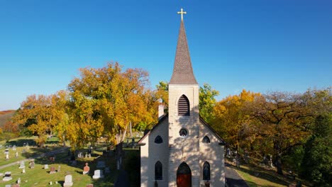 Colorful-Autumn-Trees-With-Small-Catholic-Church-And-Cemetry-Drone