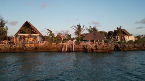 Turistas-En-El-Resort-De-Bungalows-En-La-Playa-Cerca-Del-Océano-Índico,-Tiro-Aéreo-A-La-Derecha