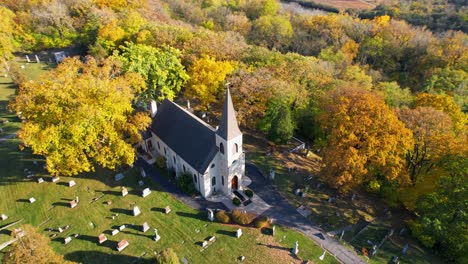 Pequeña-Iglesia-Católica-Rural-Y-Cementerio-Con-árboles-De-Otoño-De-Colores-Brillantes-Drone