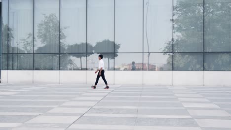 Indian-entrepreneur-walking-near-glass-office-with-his-own-reflection