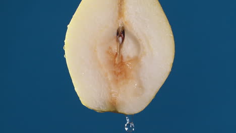 Yellow-half-pear-on-a-blue-dark-background-with-drops-of-water-rolling-down-the-pear-and-flowing-splashing-with-isolated-background