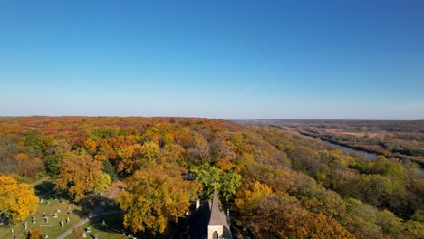 Old-Rural-Catholic-Church-With-Colorful-Autumn-Forest-And-Blue-Sky-Drone