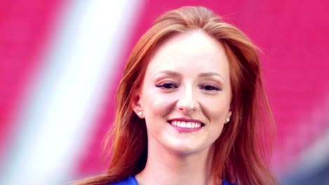 Beautiful-young-red-hair-woman-smiling-with-the-stadium-on-the-background