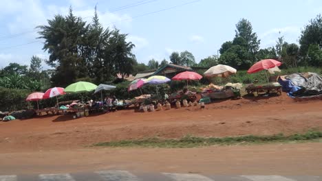 Handheld-documentary-style-shaky-footage-of-a-traditional-African-market-along-the-road-as-cars-passing-by