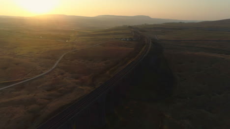 Aerial-Drone-Shot-Over-Ribblehead-Viaduct-Train-Bridge-at-Stunning-Sunrise-in-Summer-in-Yorkshire-Dales-England-UK-with-Hills-in-Background