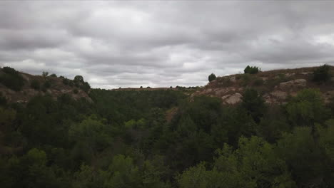 Aerial-dolly-forward-shot-of-beautiful-nature-in-georgia-with-a-forest,-rocks-and-the-cloudy-sky-in-the-background-in-slow-motion