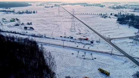 Cinematic-aerial-shot-of-European-roadways-and-rail-track-close-to-each-other-and-vast-landscape-covered-with-snow-and-dramatic-sky