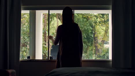 Silhouette-of-young-woman-looking-out-of-window,-stay-home-in-quarantine