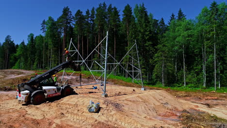 Aerial-rotation-revealing-professional-worker-installing-high-voltage-tower-in-forest-firebreak