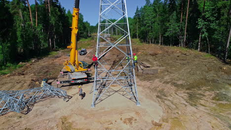 Workers-installing-a-high-voltage-tower-with-crane-in-the-woods