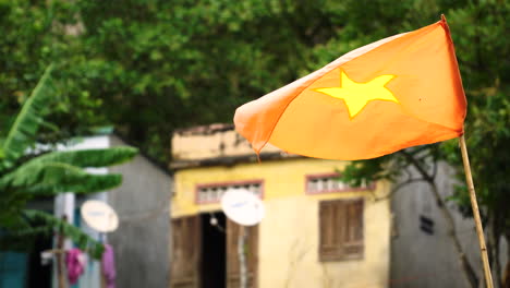 Bandera-Vietnamita-En-Una-Piscina-De-Palos-De-Bambú-Ondeando-Con-Una-Casa-Rural-Pobre-En-Una-Parte-Pobre-Y-Remota-Del-País
