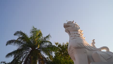 Slow-motion-rotating-shot-over-temple-Lion-statue-looking-up-at-blue-sky